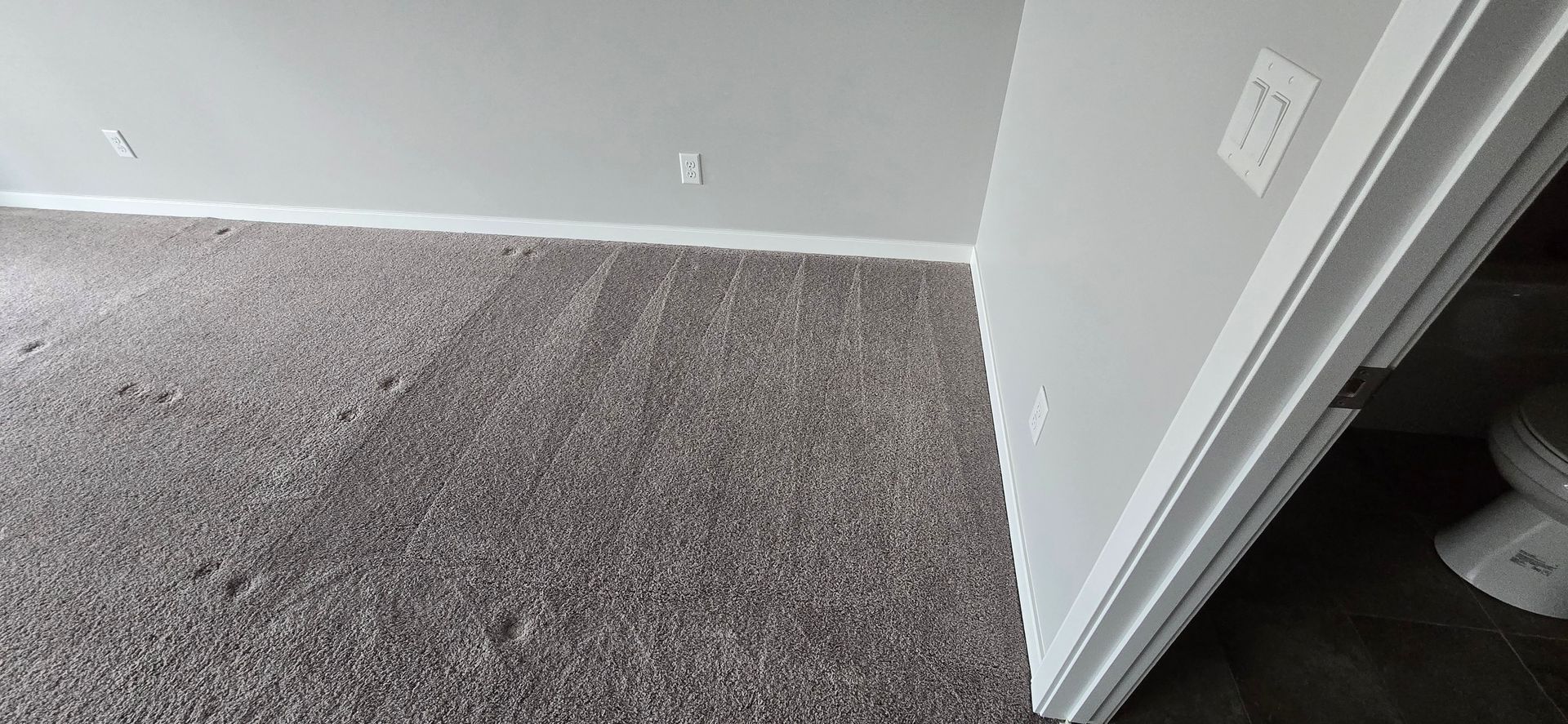 A room with gray walls, carpet, and a white door frame.