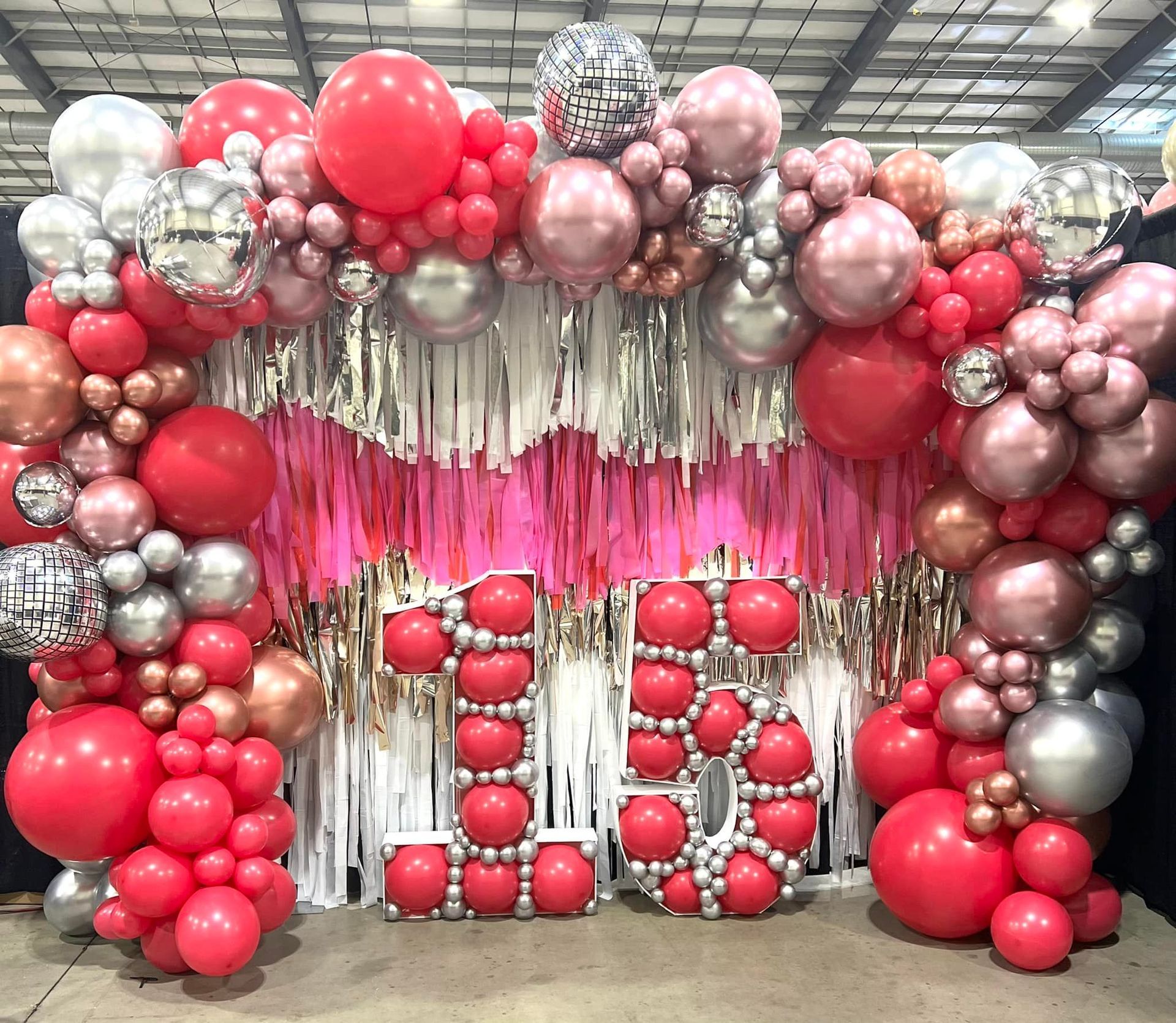 a bunch of balloons are sitting in front of a wall