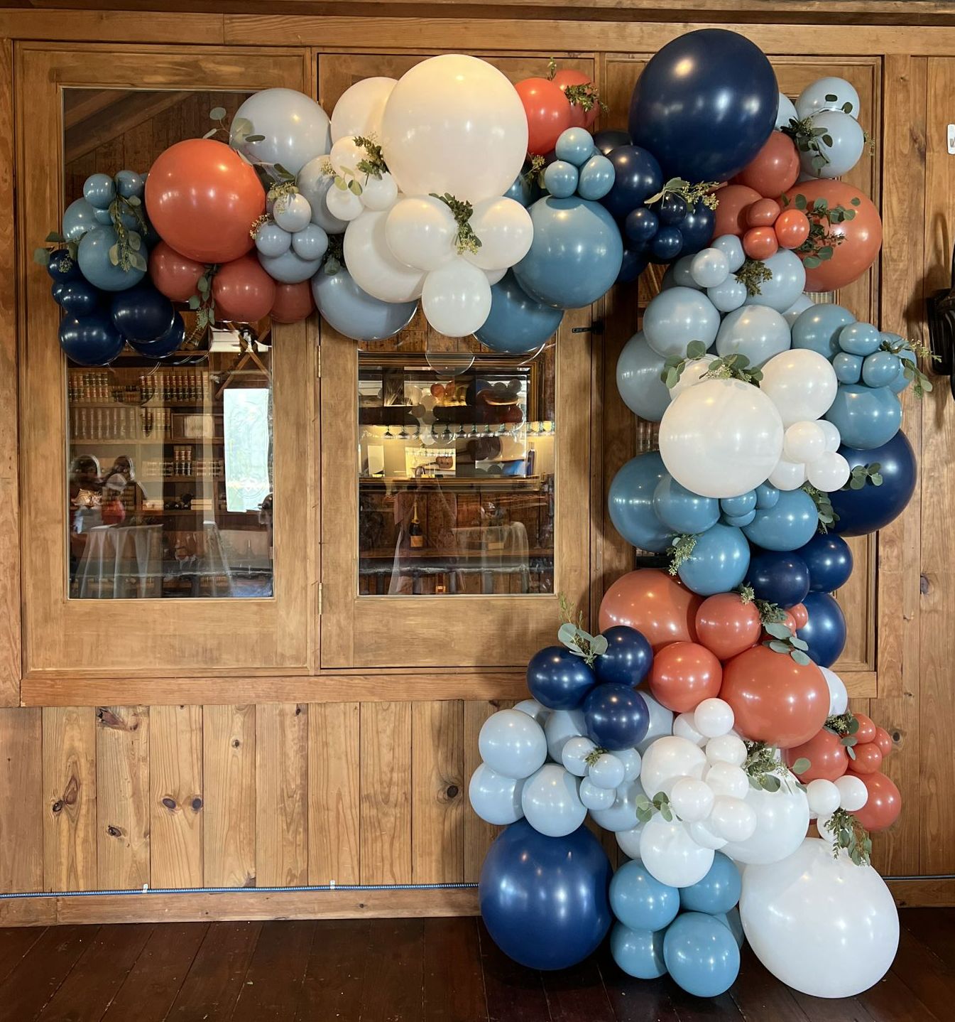a bunch of balloons are hanging on a wooden wall