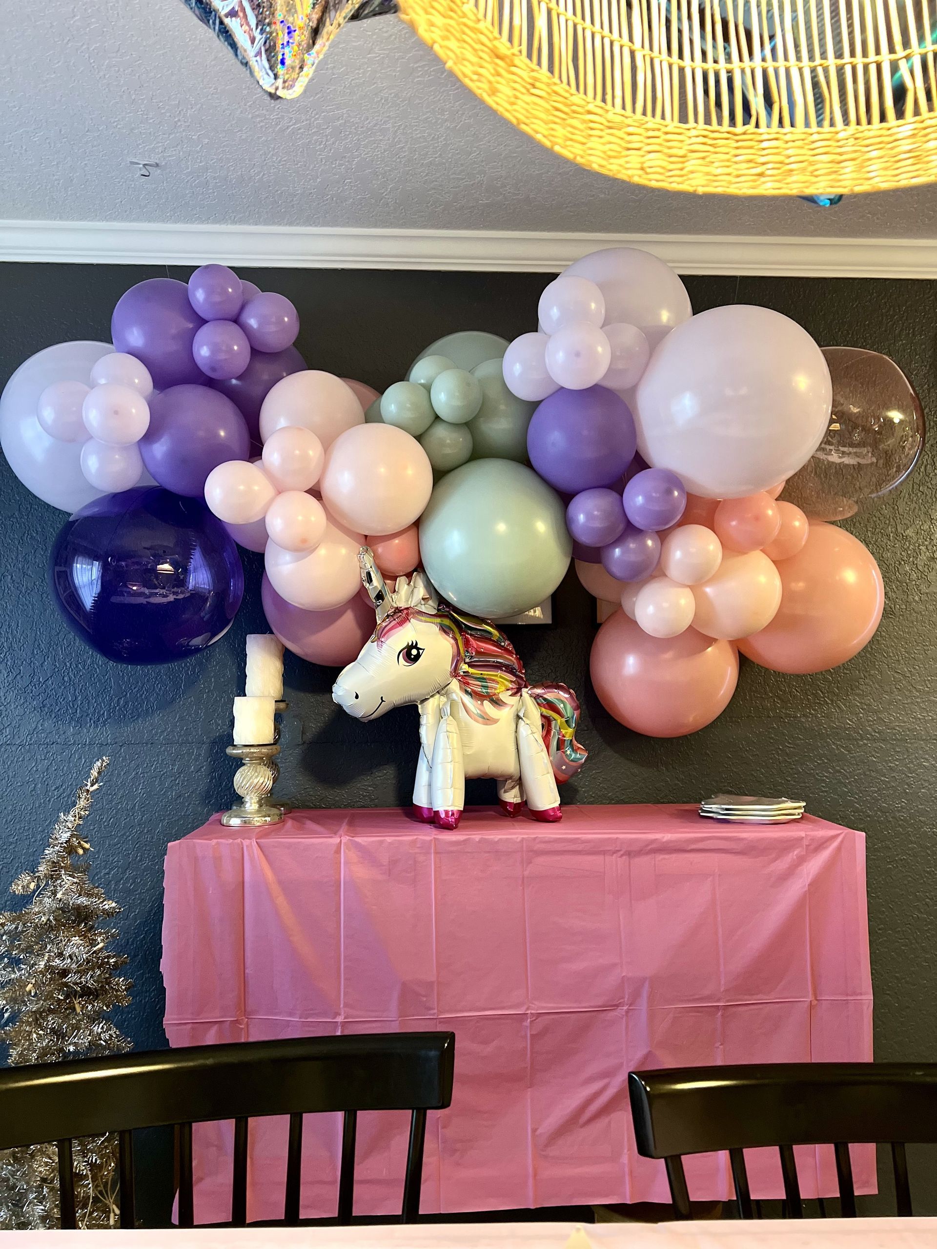 a table with a pink tablecloth and balloons on it