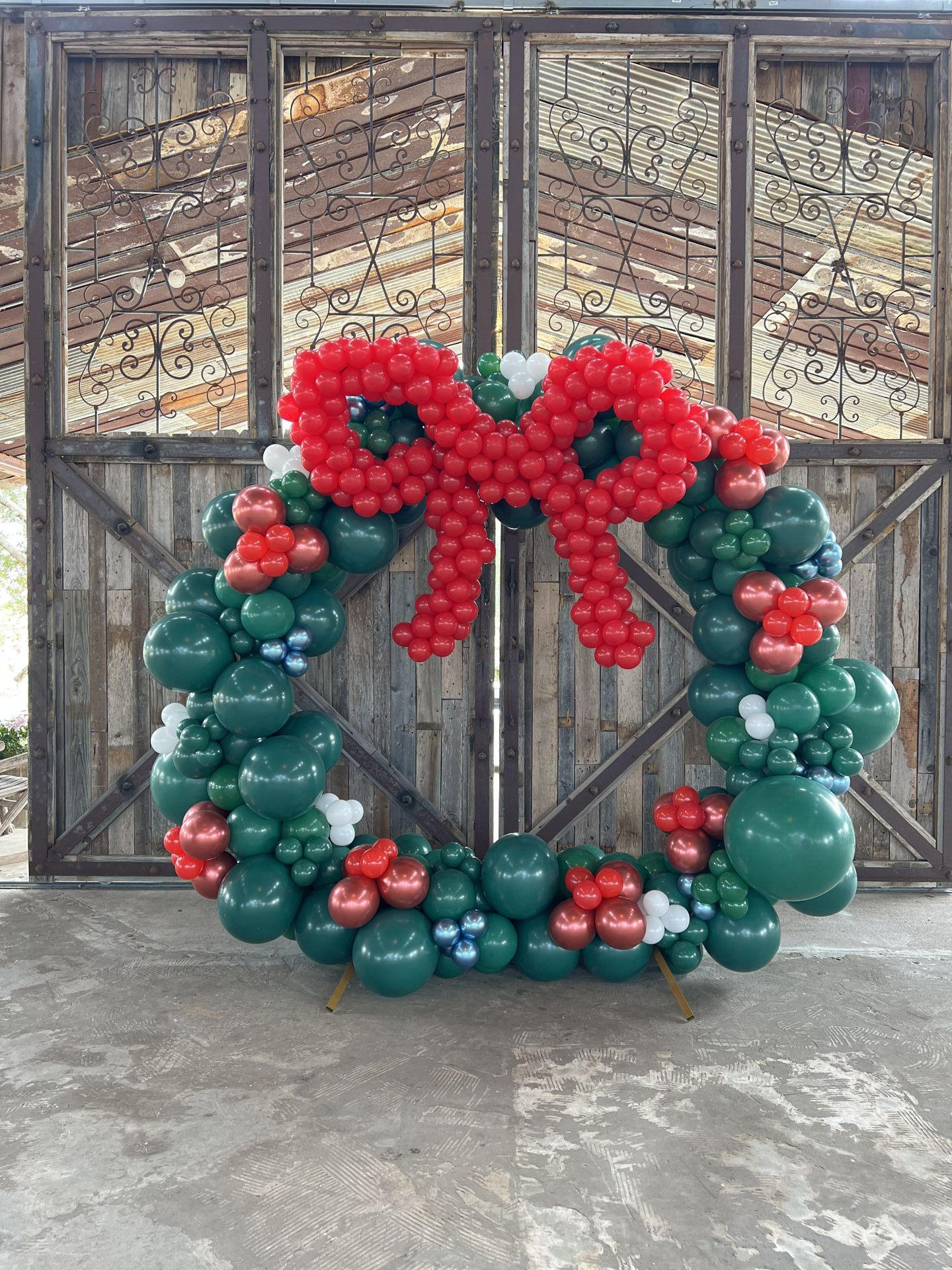 a christmas wreath made of balloons is sitting in front of a wooden gate