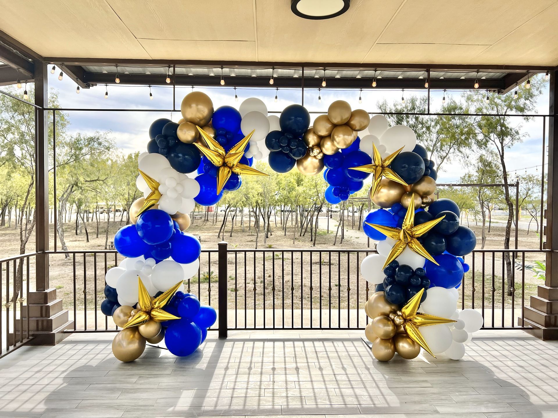 a large arch made of blue , white , and gold balloons