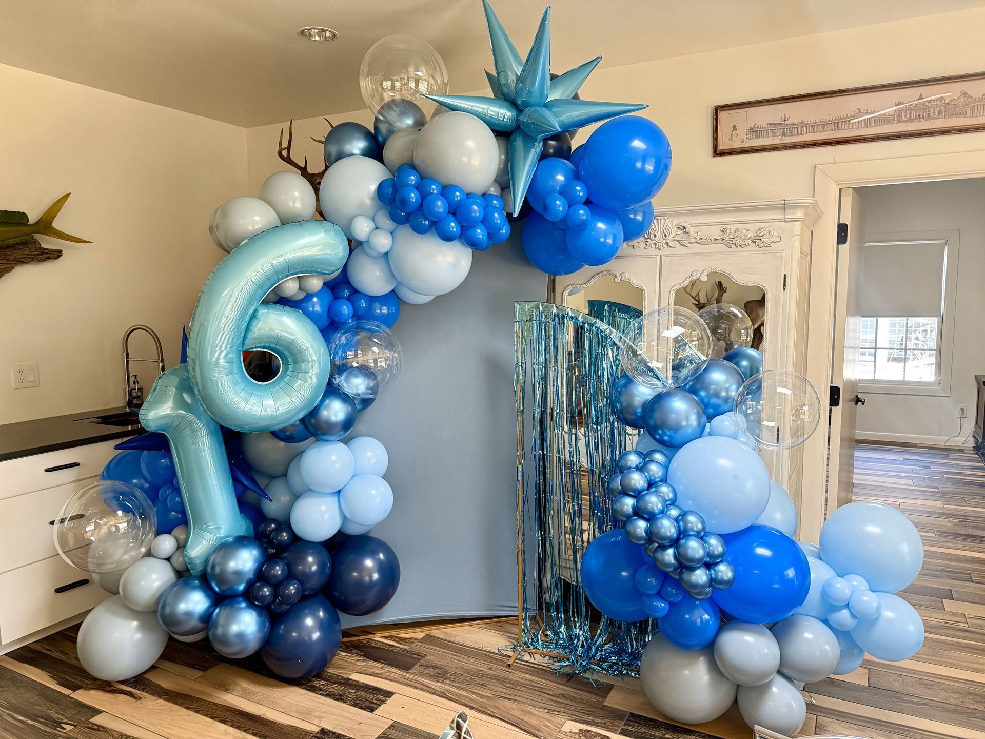 A room filled with blue and white balloons and a number 6 balloon.