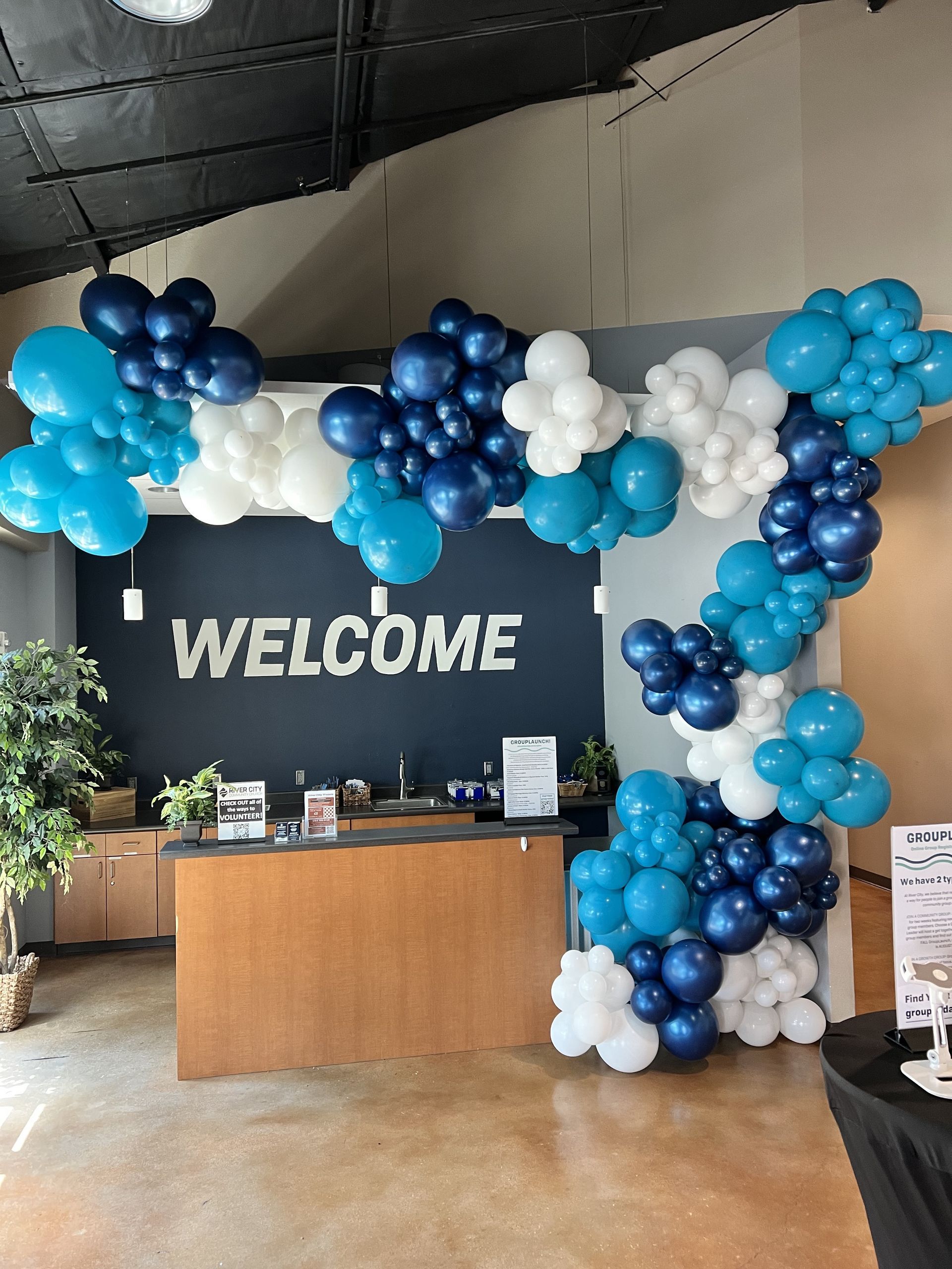 a welcome sign is surrounded by blue and white balloons