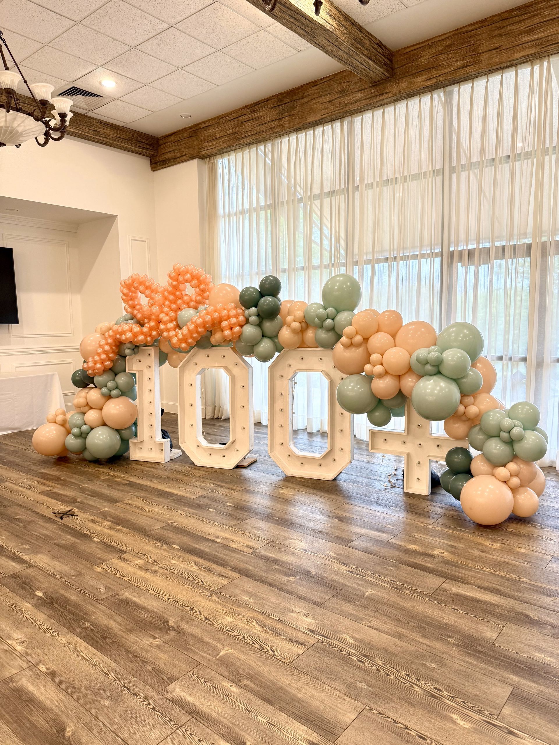 A room filled with balloons and a sign that says 100.