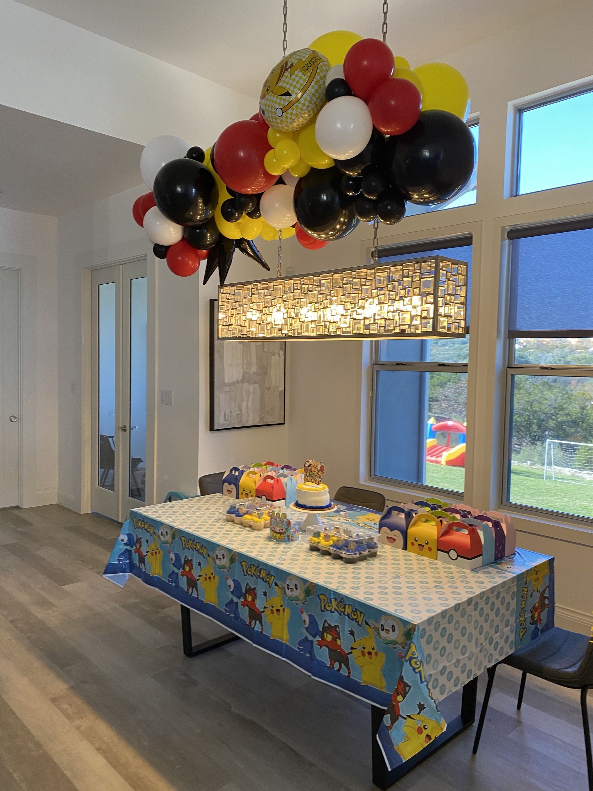 a table with a pikachu tablecloth and balloons hanging from the ceiling