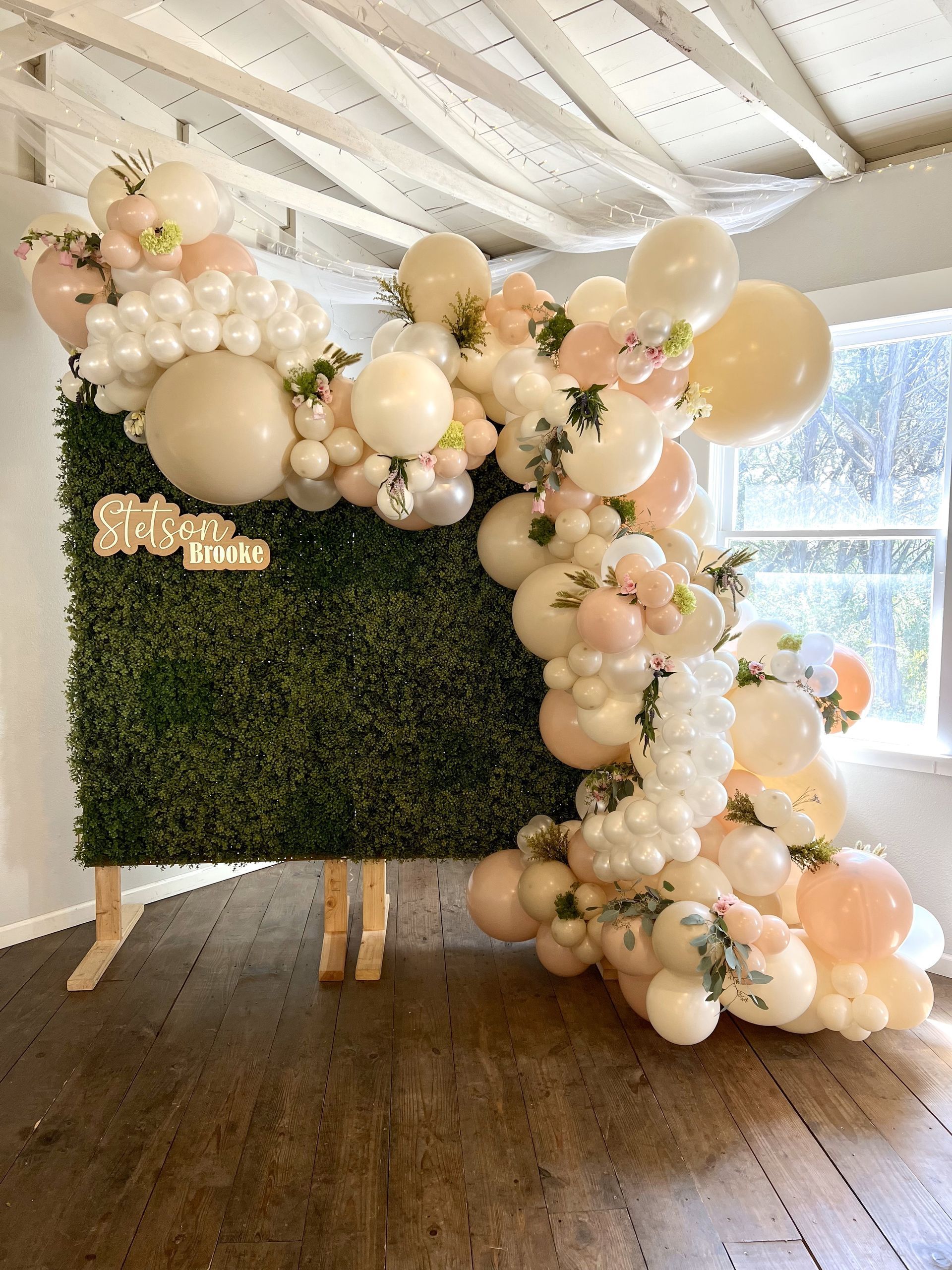 A wall with balloons and flowers on it in a room.