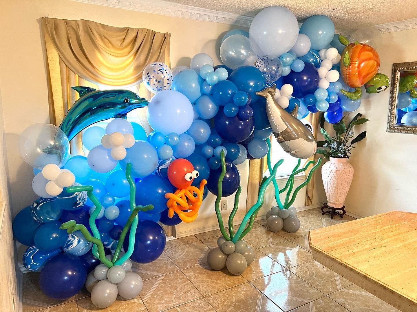 A room decorated with balloons in the shape of dolphins , octopus , and seaweed.