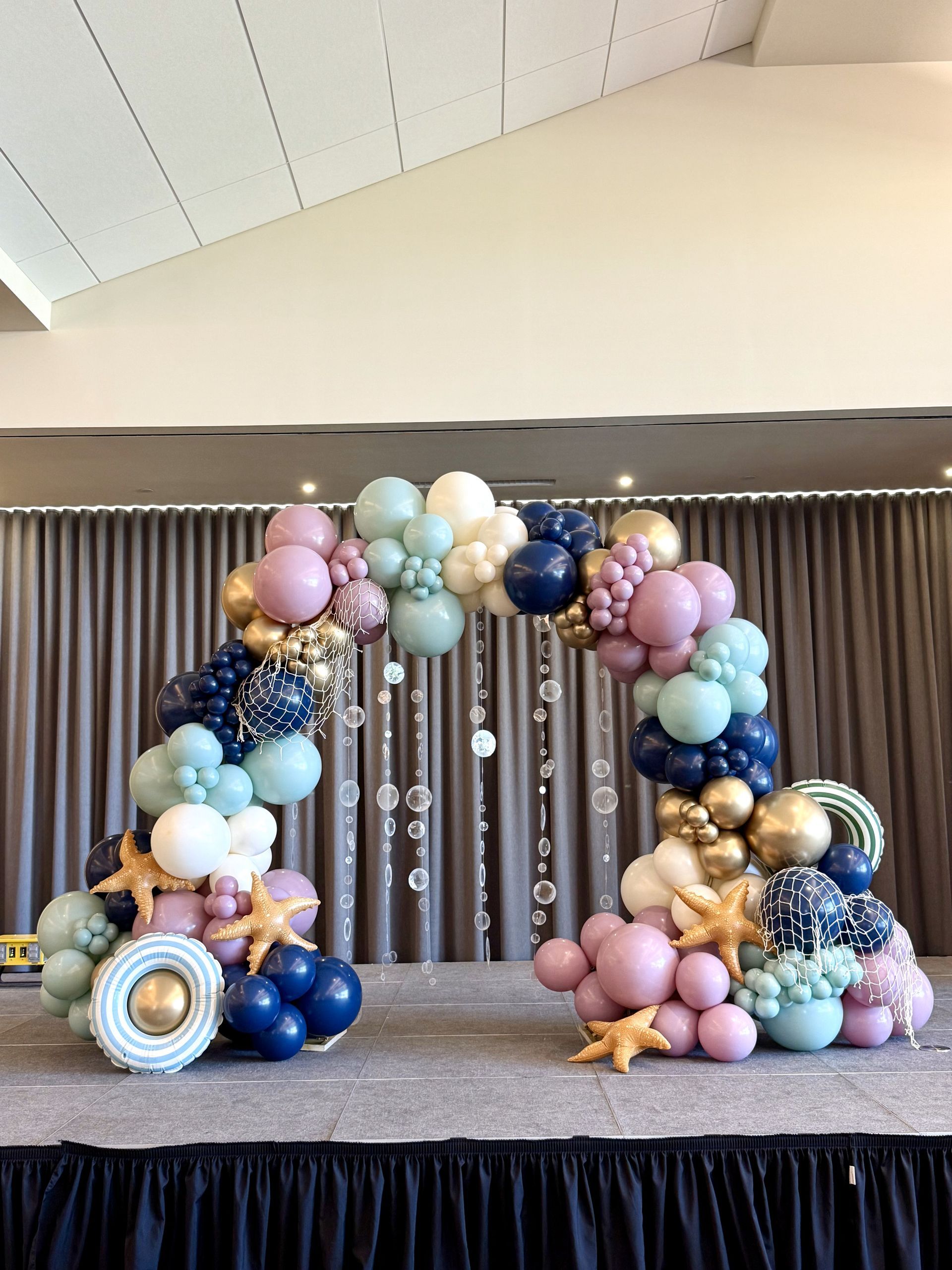 A balloon arch is sitting on top of a stage in a room.