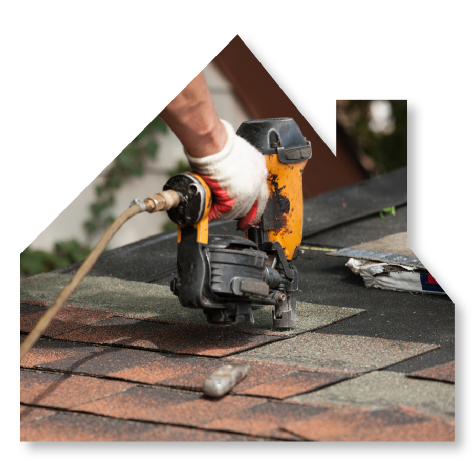 A close-up of a worker using a yellow pneumatic nail gun to install asphalt shingles on a roof.