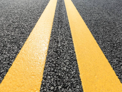 Bright white line striping being painted on a newly paved parking lot for clear traffic guidance