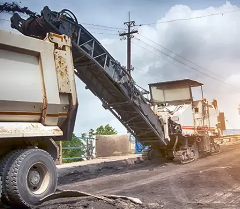 Close-up of asphalt milling machine removing deteriorated pavement for road restoration