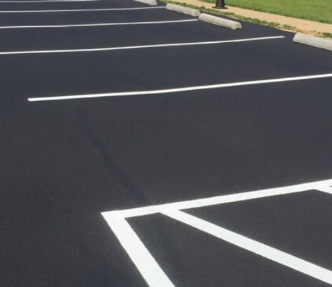 Professional applying precise asphalt line striping for parking lot organization and safety