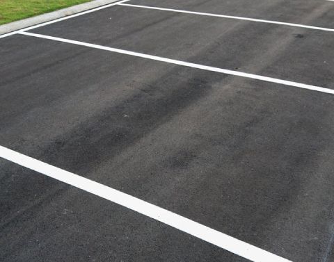 Experienced crew painting clean, bright lines on asphalt surface for traffic and parking guidance