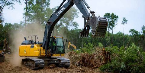 Heavy machinery performing land clearing and excavation to prepare site for construction projects