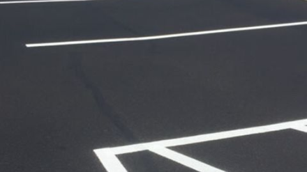 Residential asphalt driveway paving with smooth blacktop finish in front of a suburban home