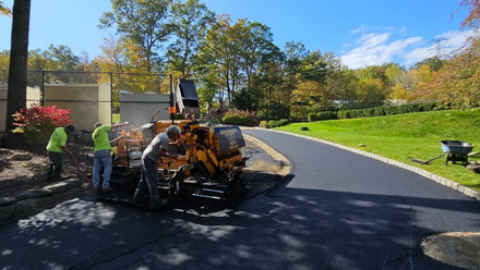 Residential asphalt driveway paving with smooth blacktop finish in front of a suburban home