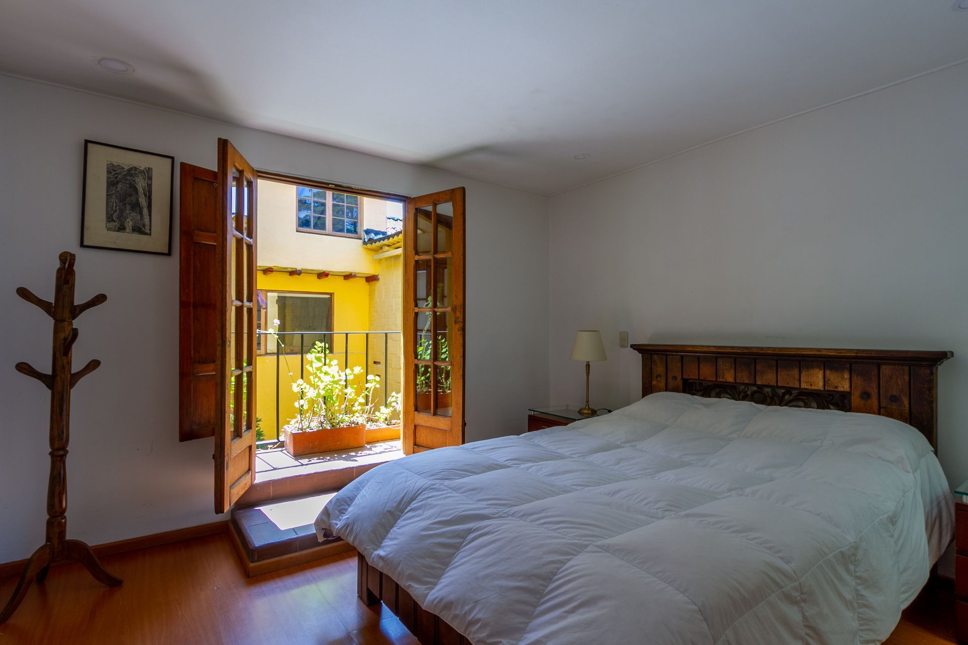A bedroom with a bed and a window with shutters open.