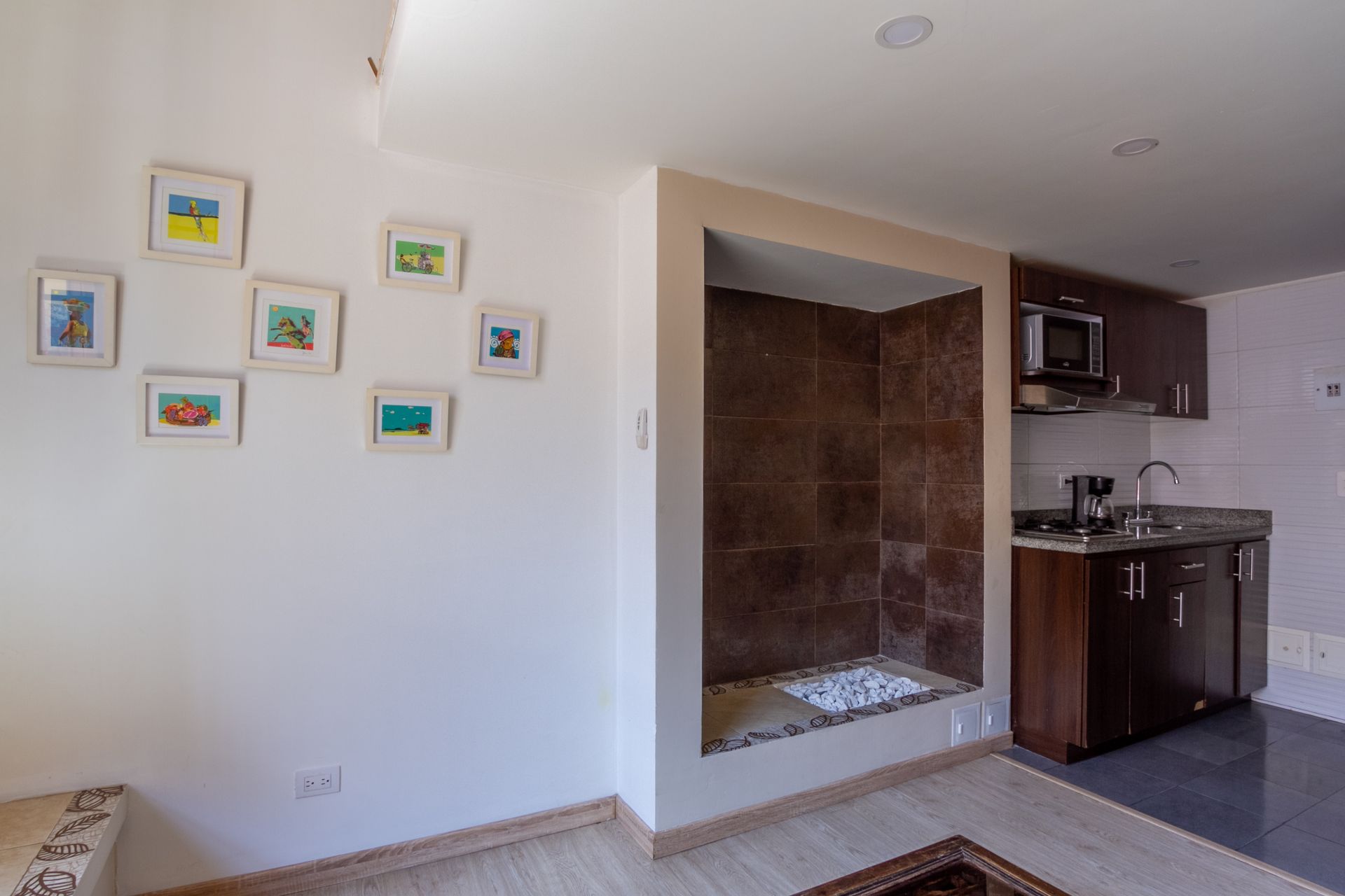 A kitchen with a sink , microwave , and dishwasher in a living room.