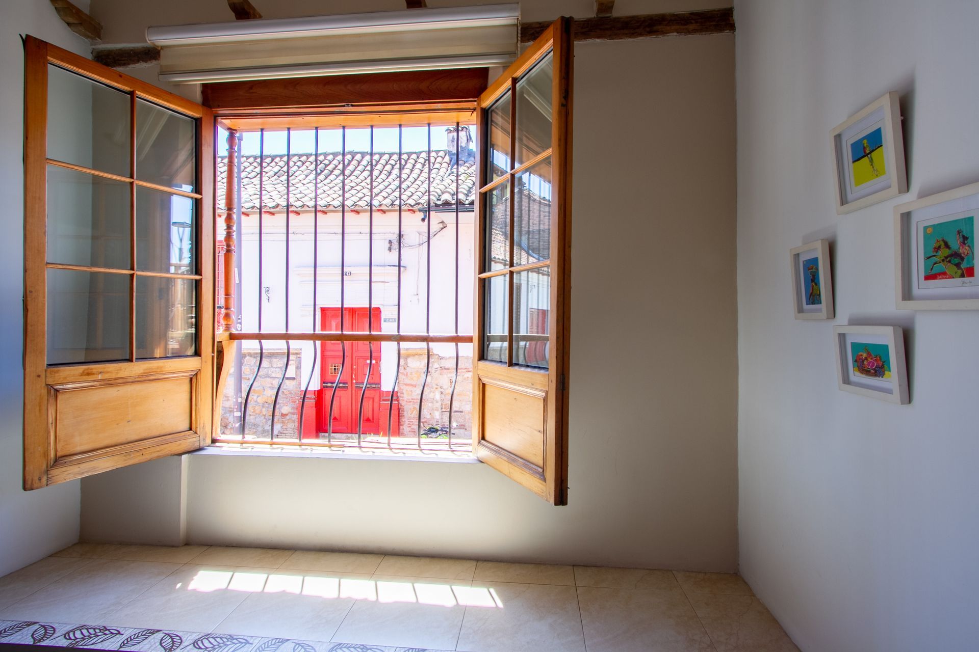 A room with a window with bars on it and paintings on the wall.