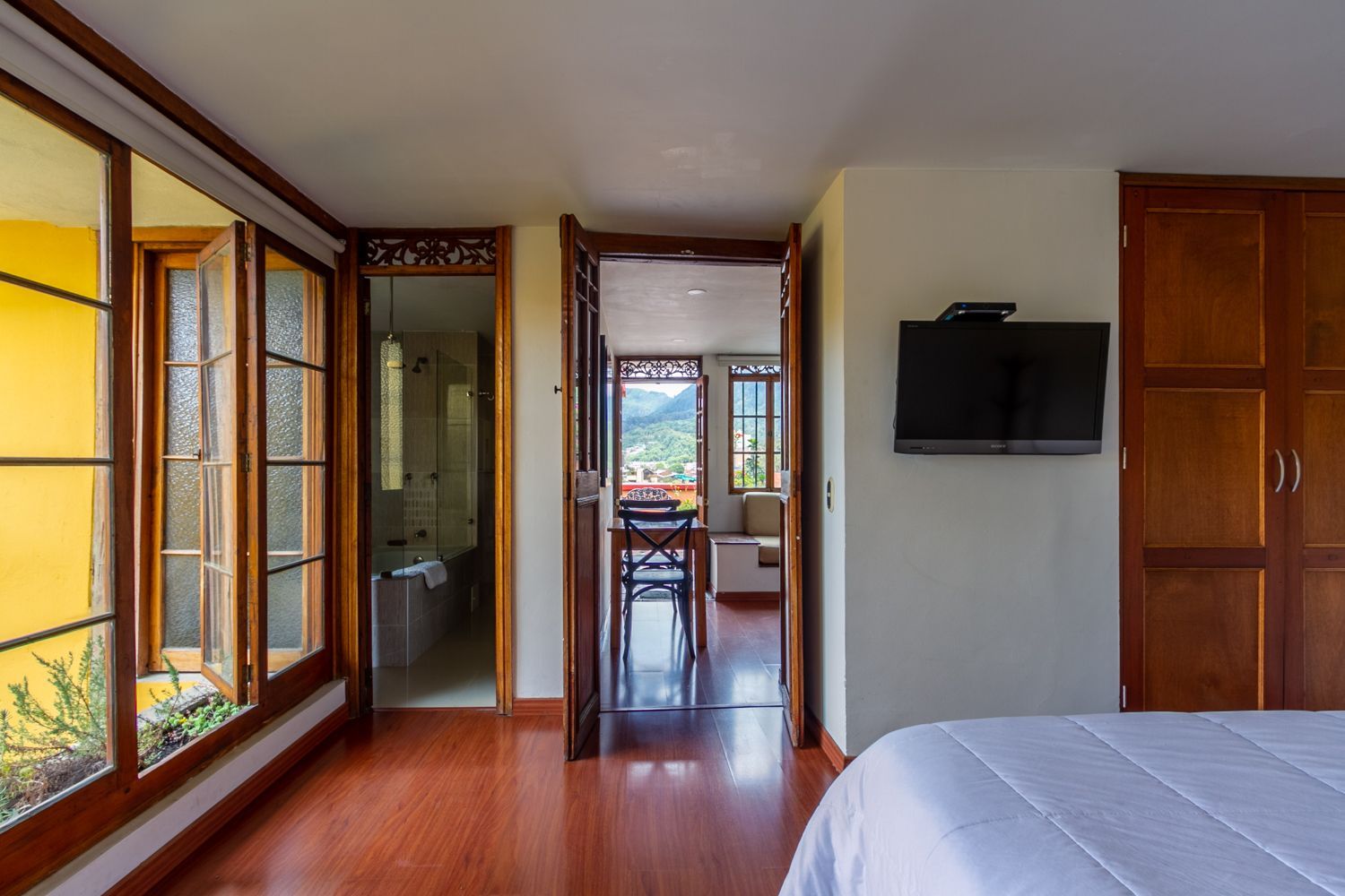 A bedroom with a bed and a flat screen tv on the wall.