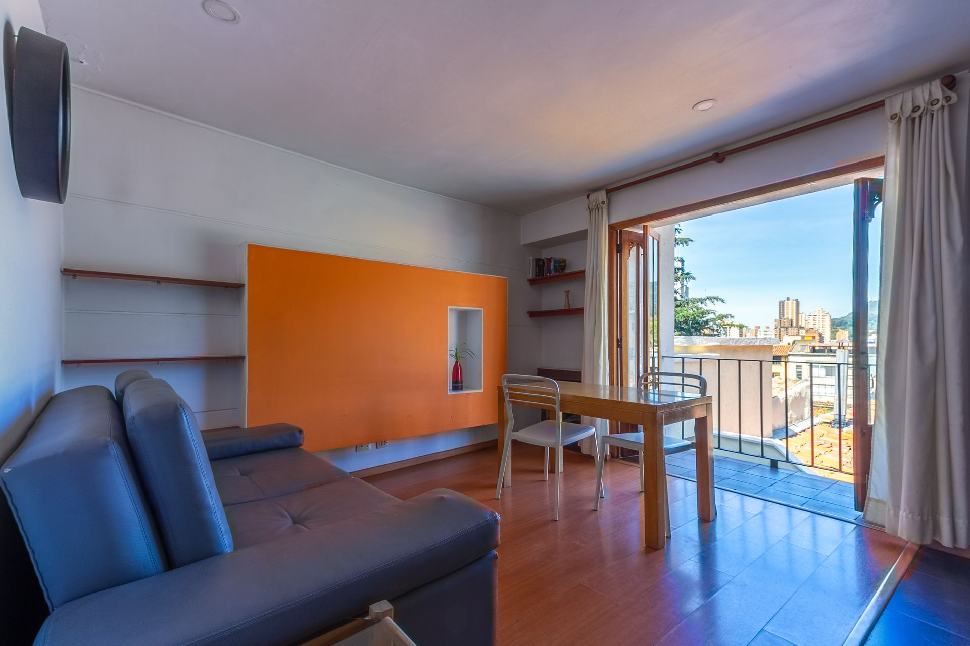 A living room with a couch , table and chairs and a balcony.