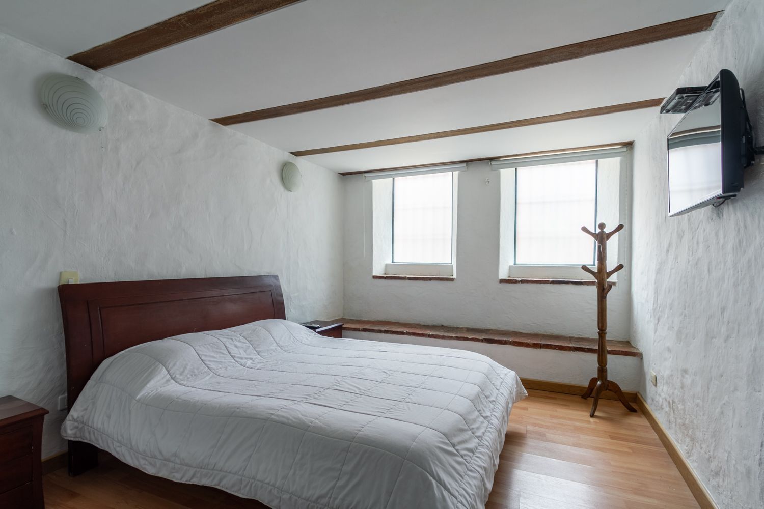 A bedroom with a bed and a television on the wall.
