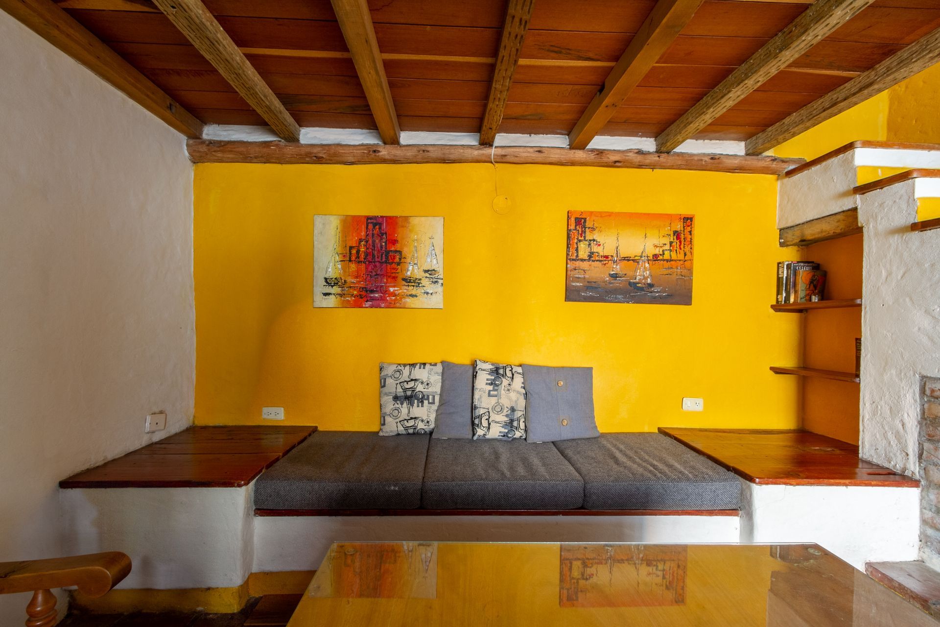 A living room with a yellow wall , a couch , a table and a fireplace.