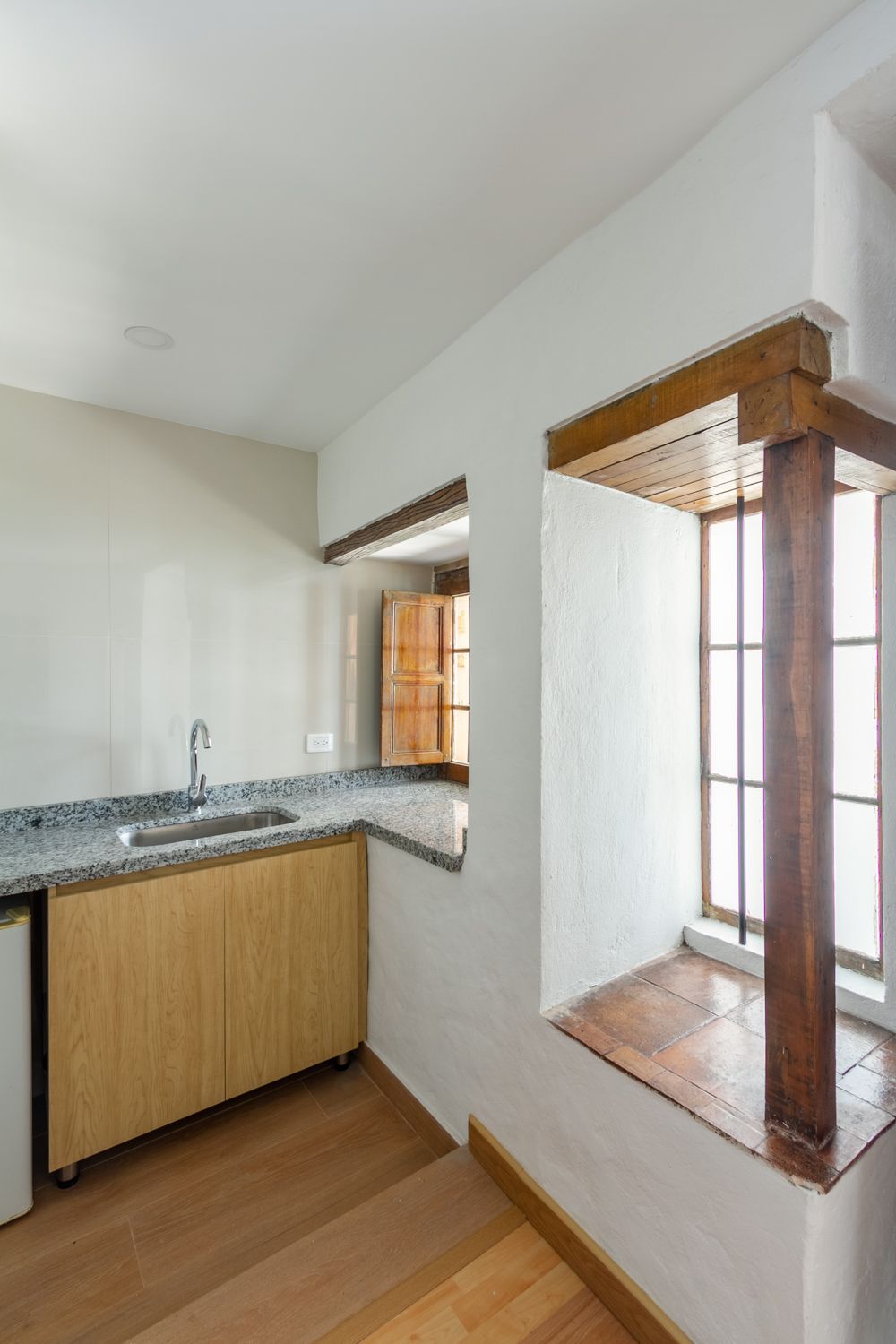 A kitchen with a sink , cabinets , and a window.