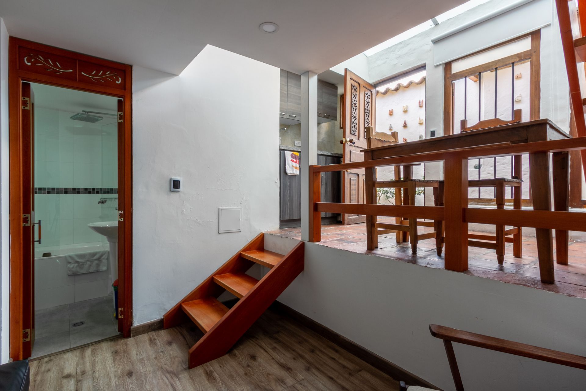 A room with wooden stairs leading up to a balcony.