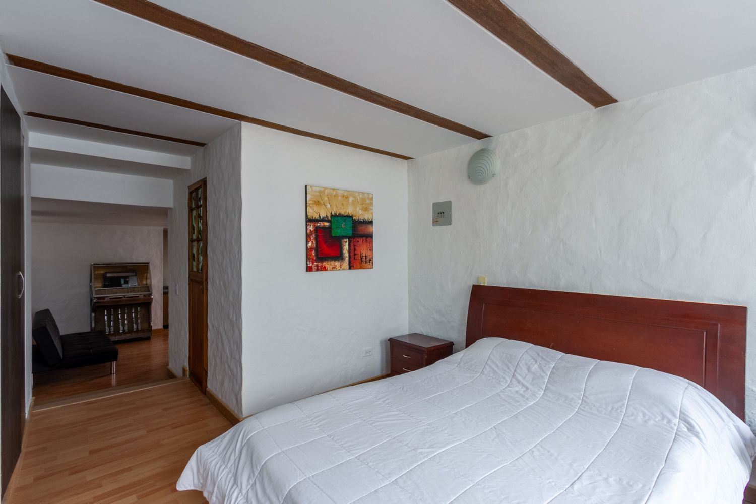 A bedroom with a bed and a painting on the wall