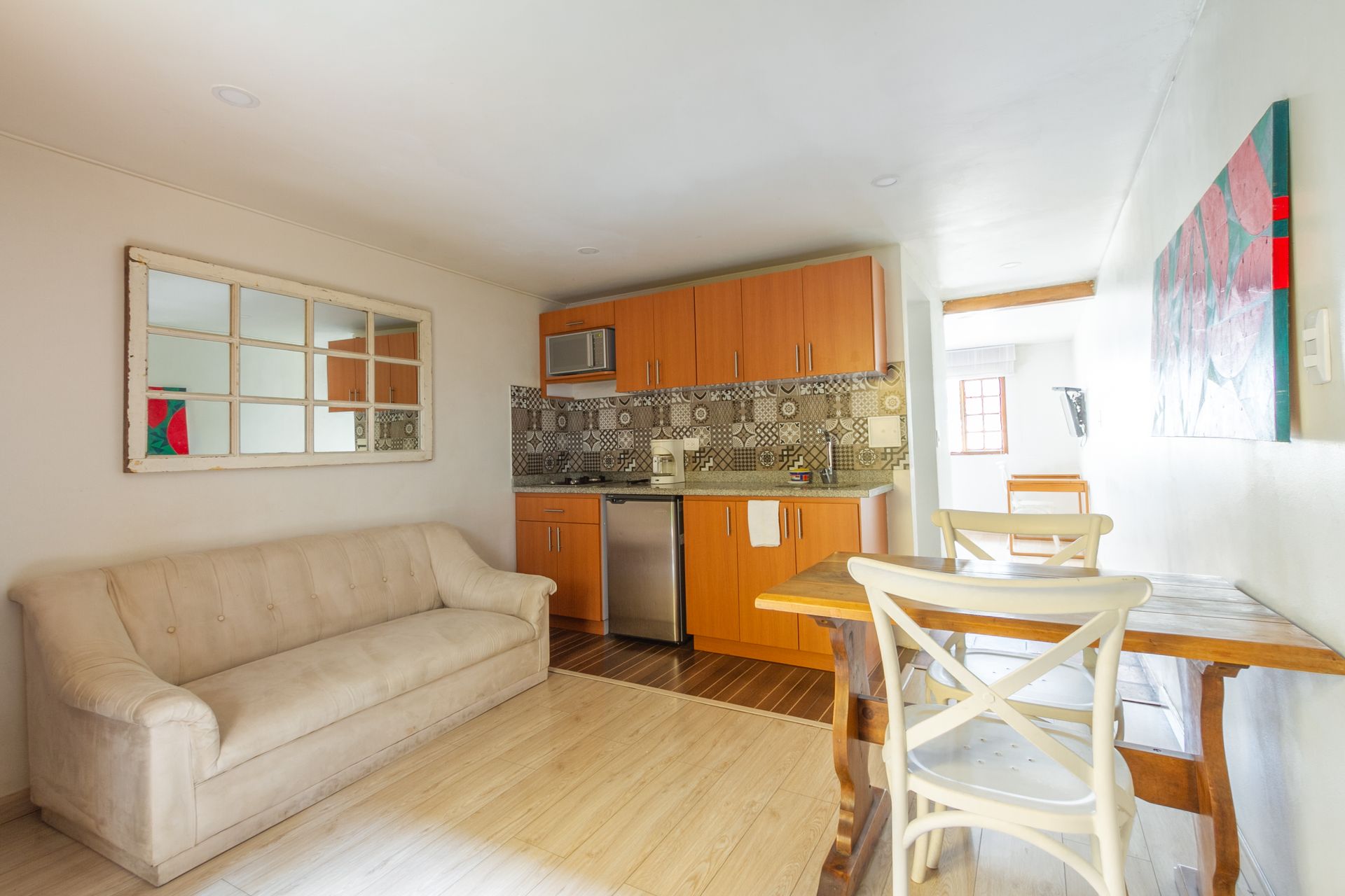 A living room with a couch , table , chairs and a kitchen.