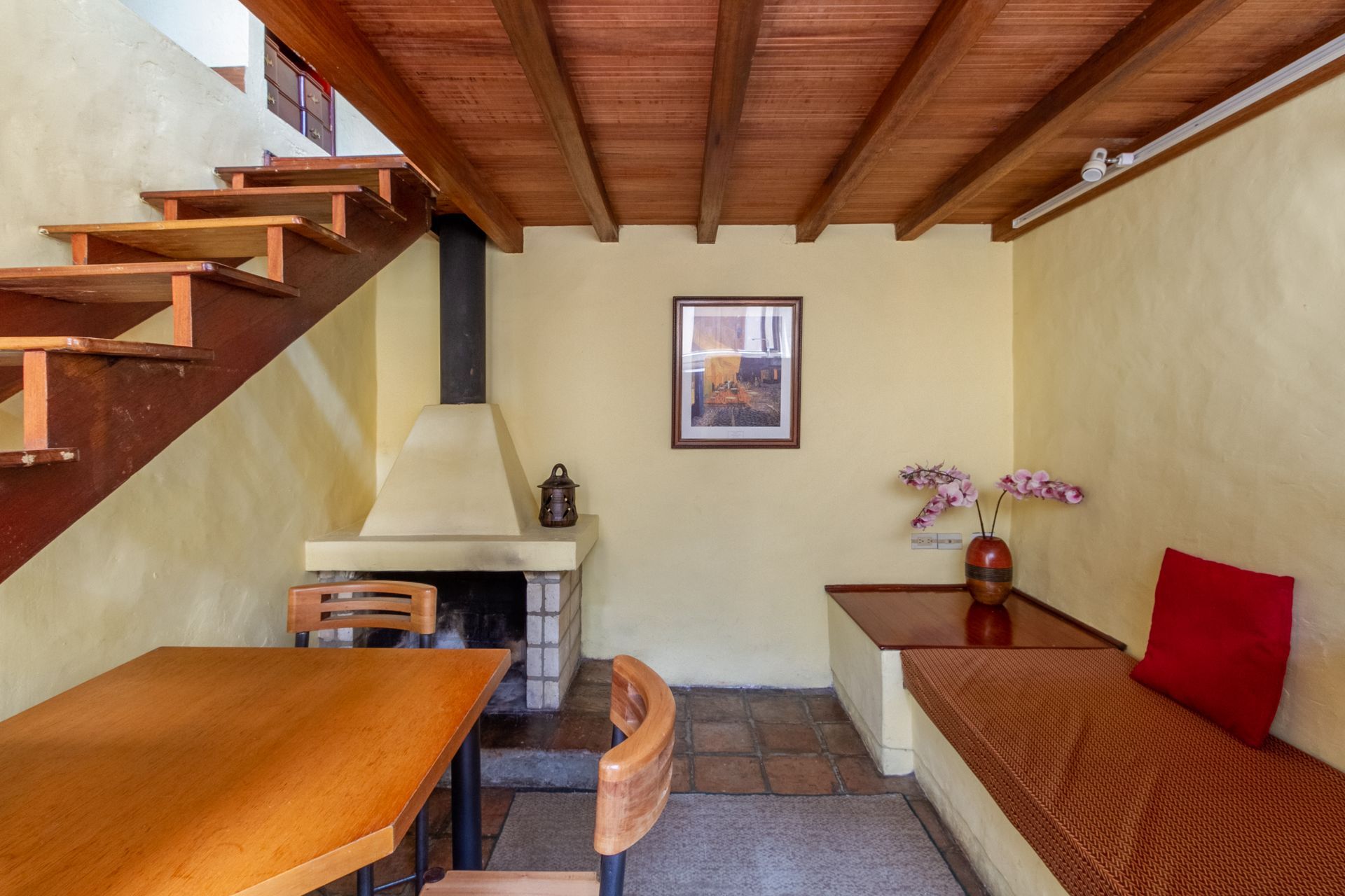 A living room with a table , chairs , fireplace and stairs.