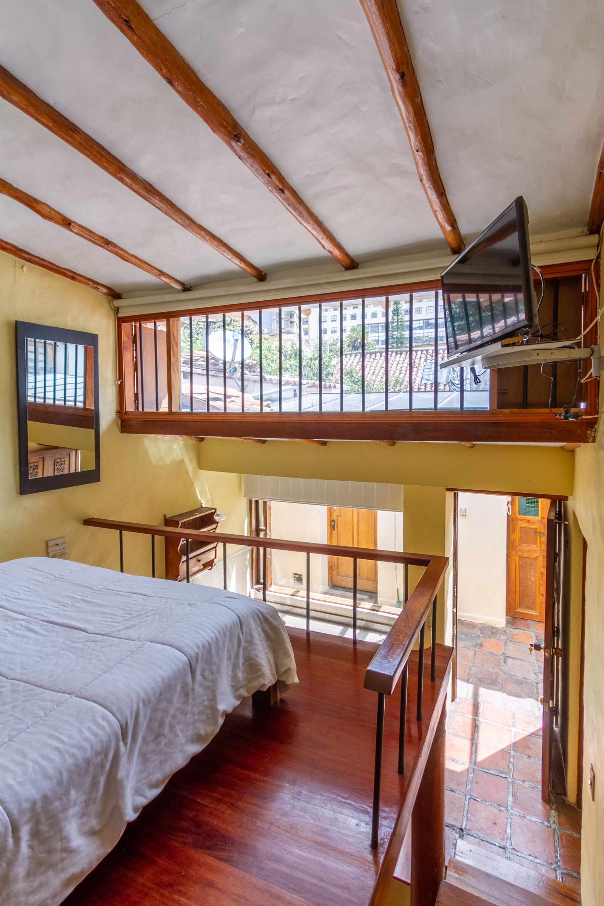 A bedroom with a bed and a television on the ceiling.