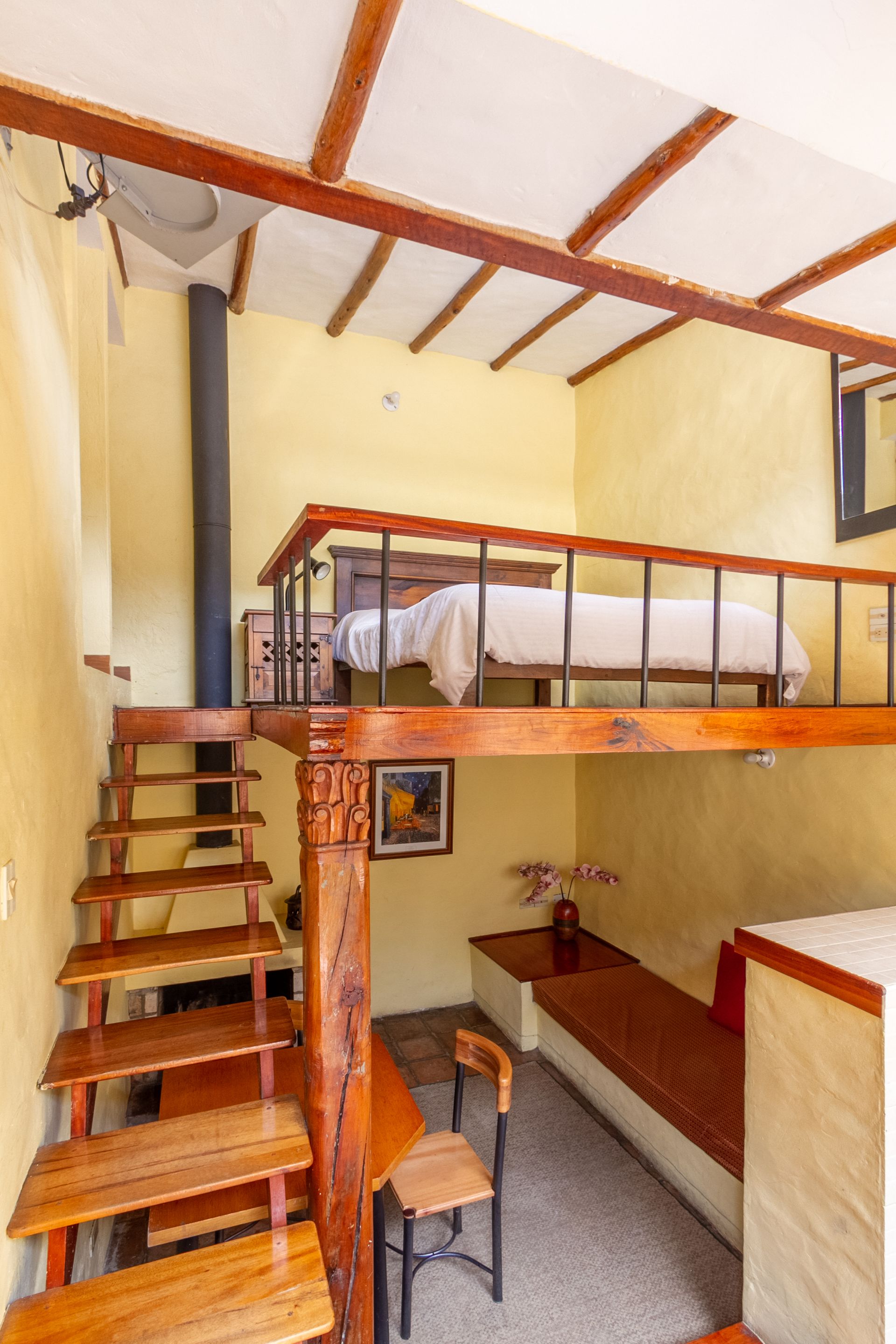 A bedroom with a bed and stairs leading to it.