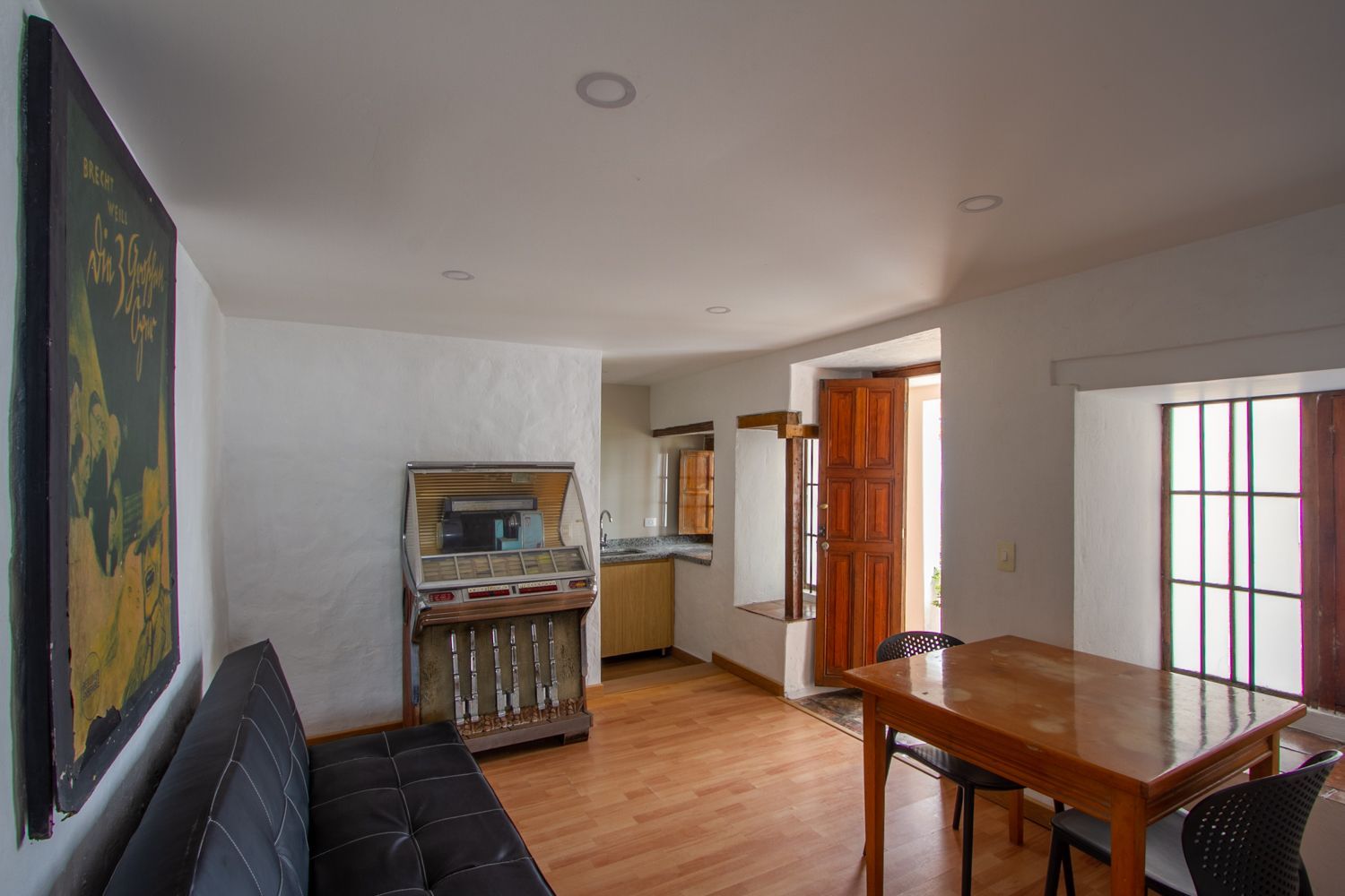 A living room with a couch , table , chairs and a jukebox.