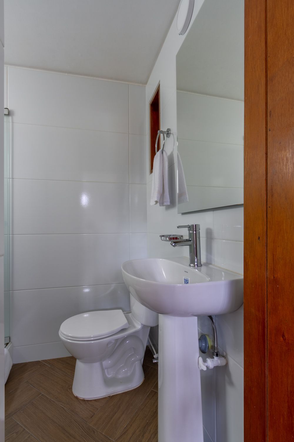 A bathroom with a toilet , sink and mirror.