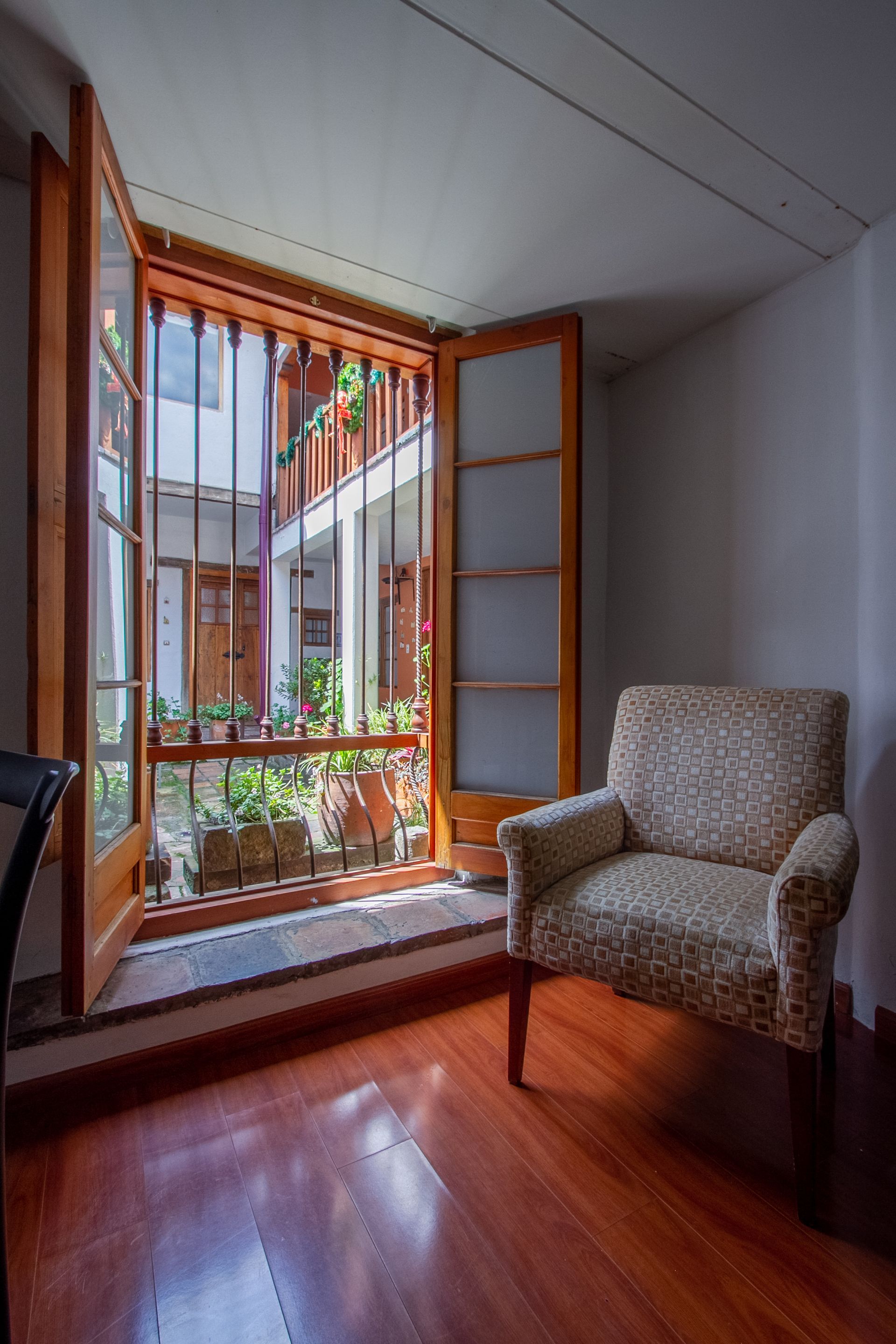 A room with a chair and a window with a view of a courtyard.
