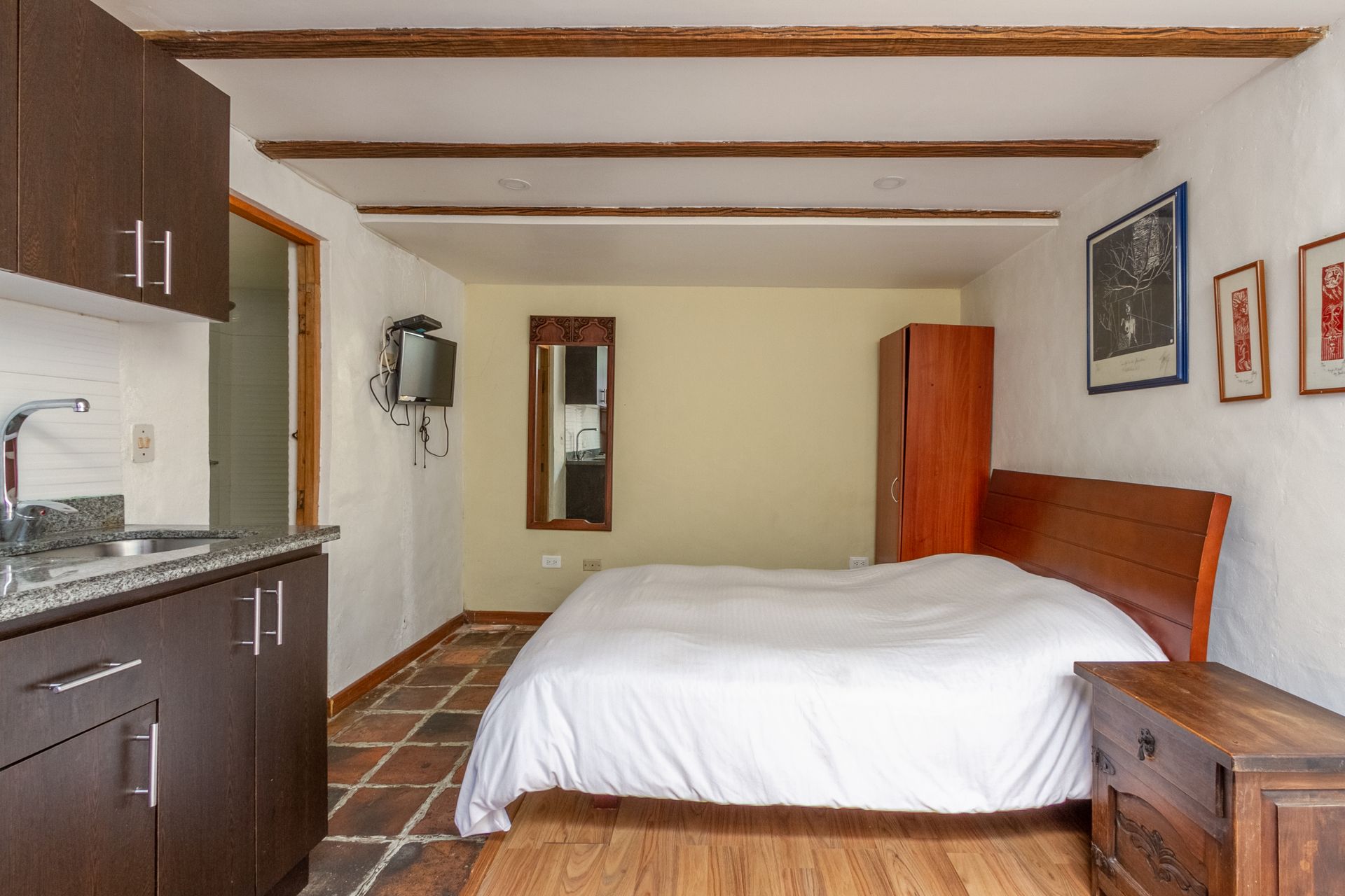 A bedroom with a bed , cabinets , a sink and a mirror.