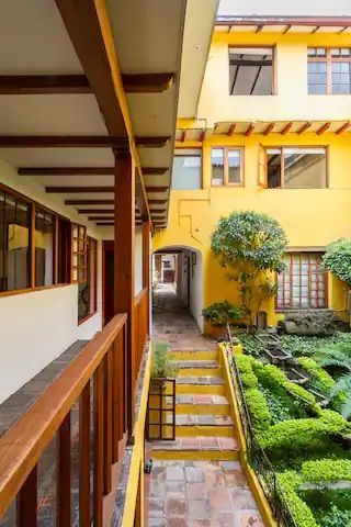 A hallway leading to a yellow building with stairs leading up to it.