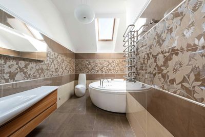 A bathroom with a tub , sink , toilet and skylight.