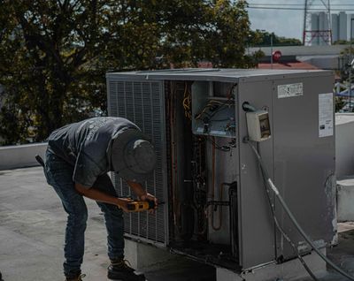 A man is working on an air conditioner on a roof.