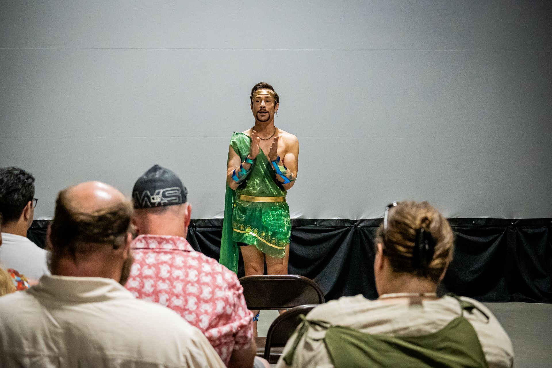 A man in a green costume is standing in front of a group of people.