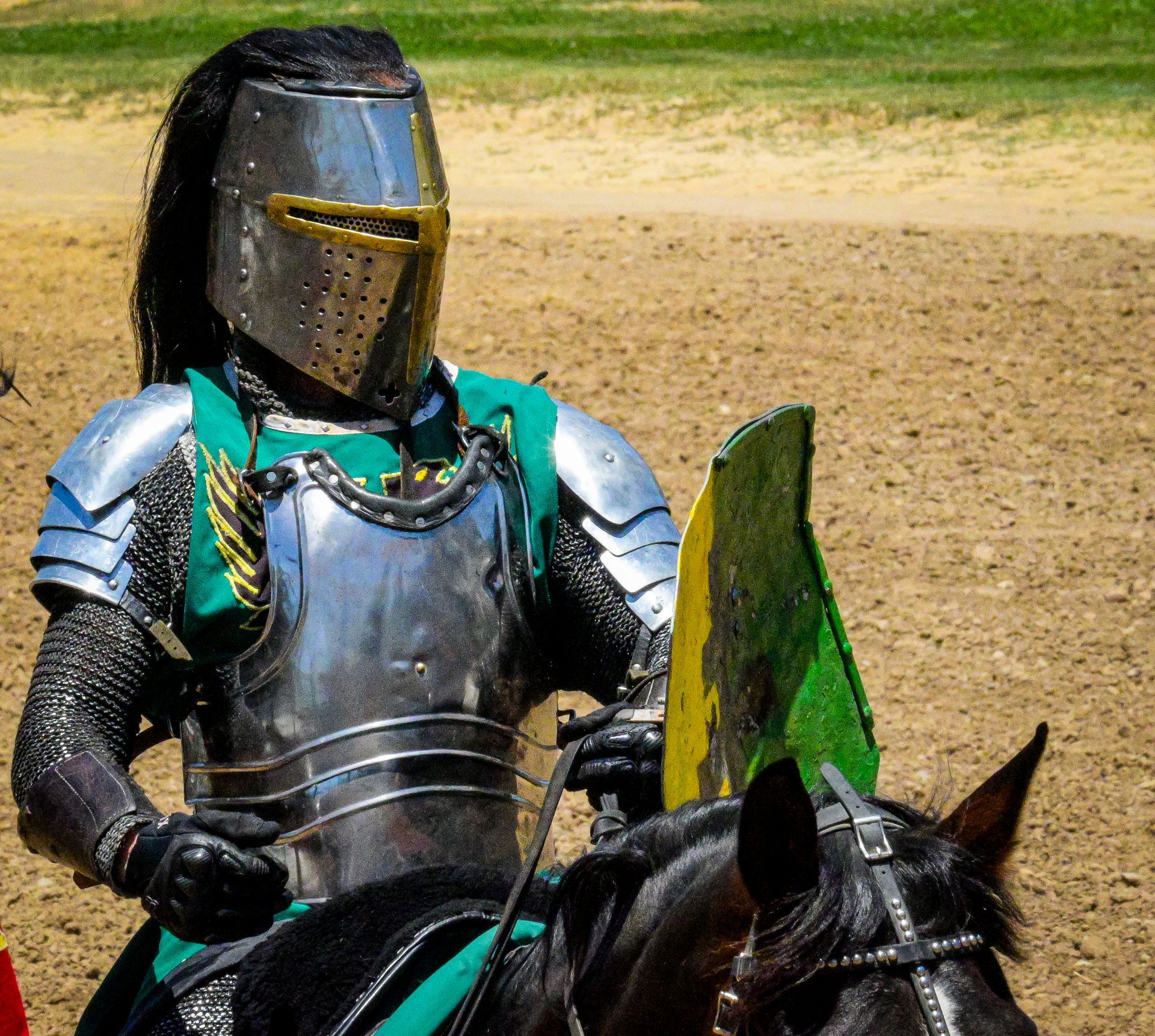 A man in armor is riding a black horse