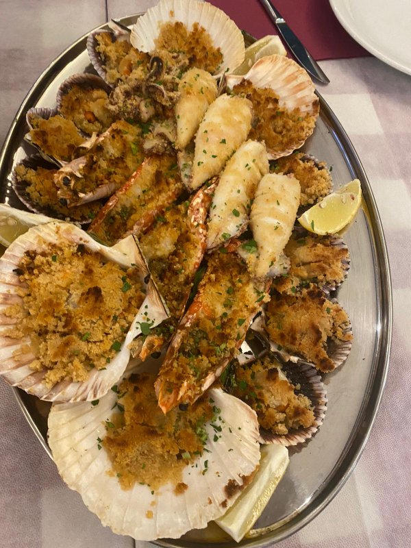 Un piatto di frutti di mare, tra cui capesante e gamberi, su un tavolo