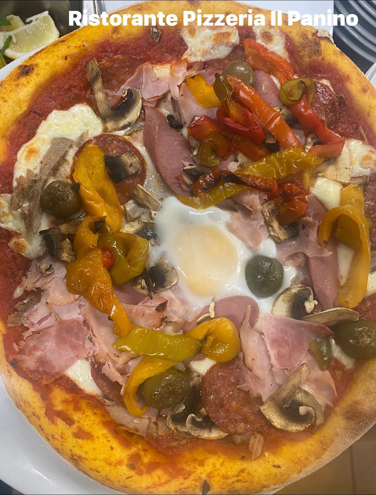 Una pizza con tanti condimenti è servita su un piatto bianco.