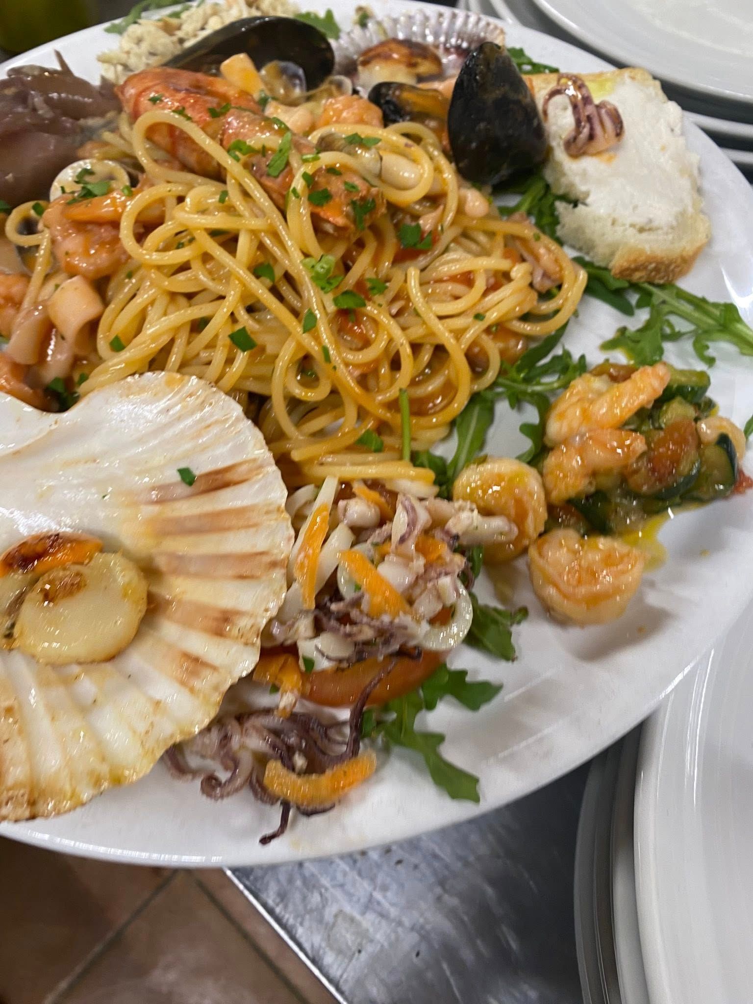 Un piatto bianco con sopra spaghetti e frutti di mare su un tavolo.