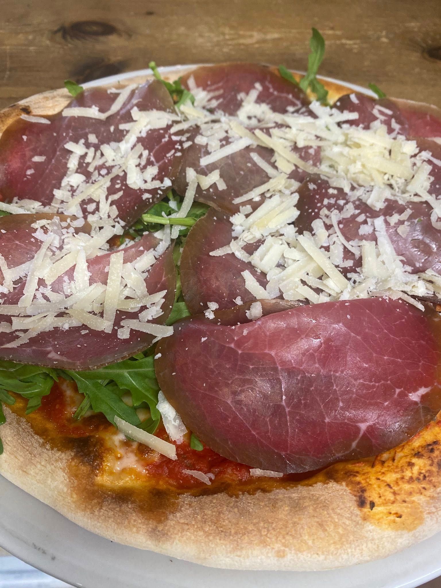 Una pizza con carne e formaggio su un piatto bianco