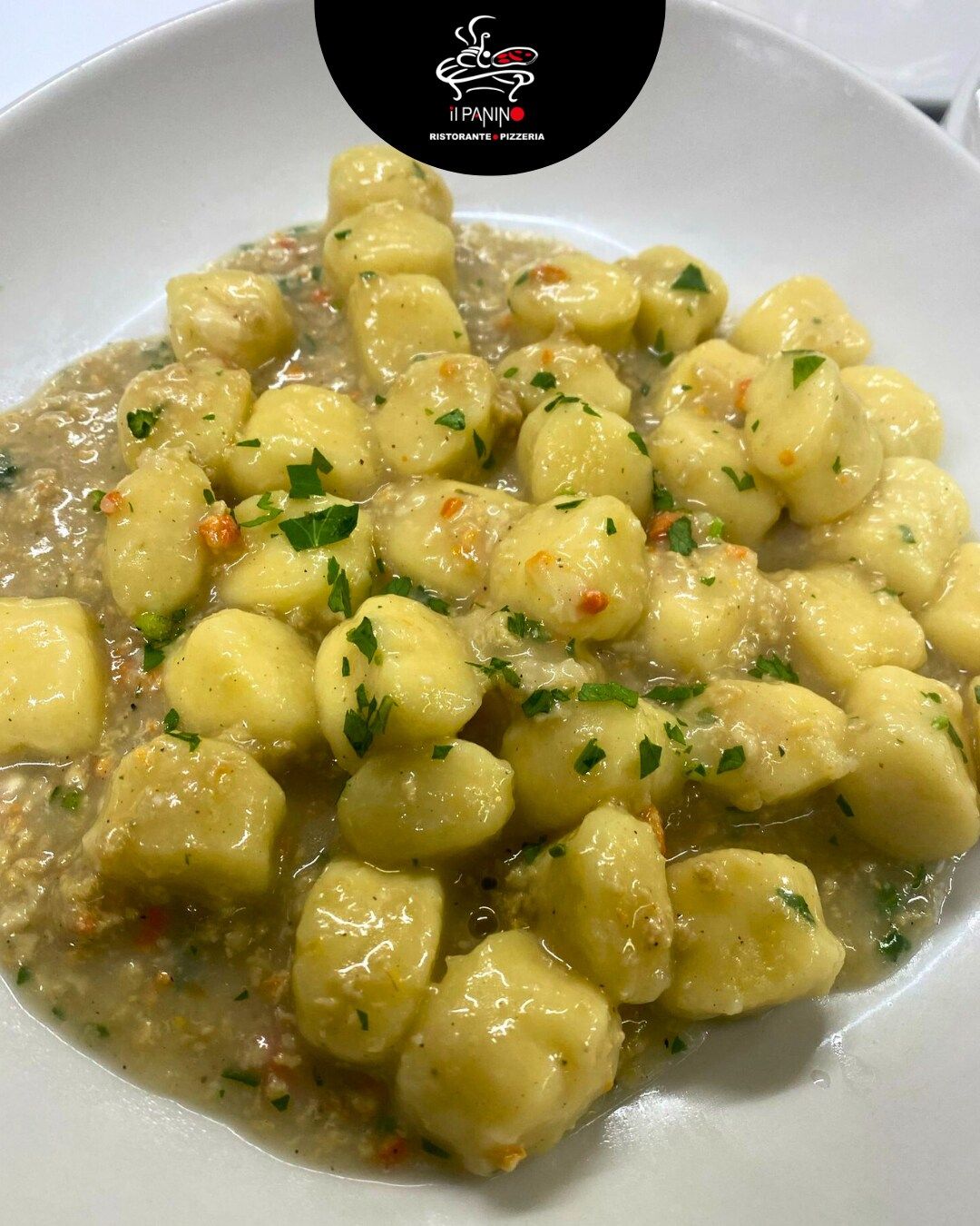 Un piatto bianco condito con gnocchi e salsa