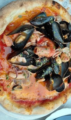 Una pizza con frutti di mare è su un piatto.